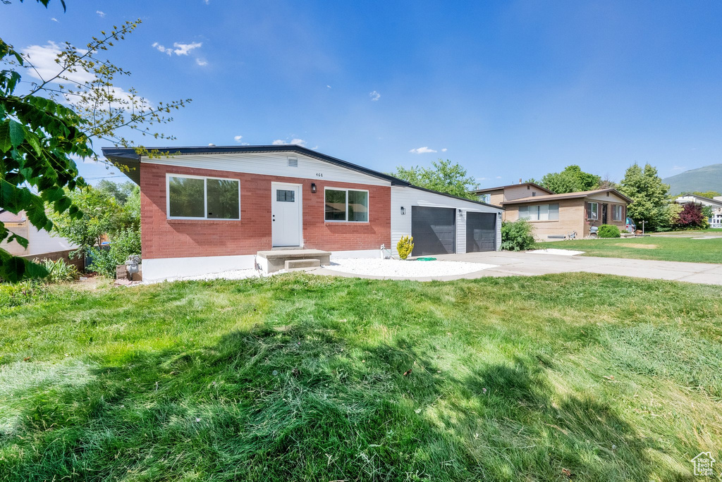 View of front of property featuring a front yard, concrete driveway, and an attached garage