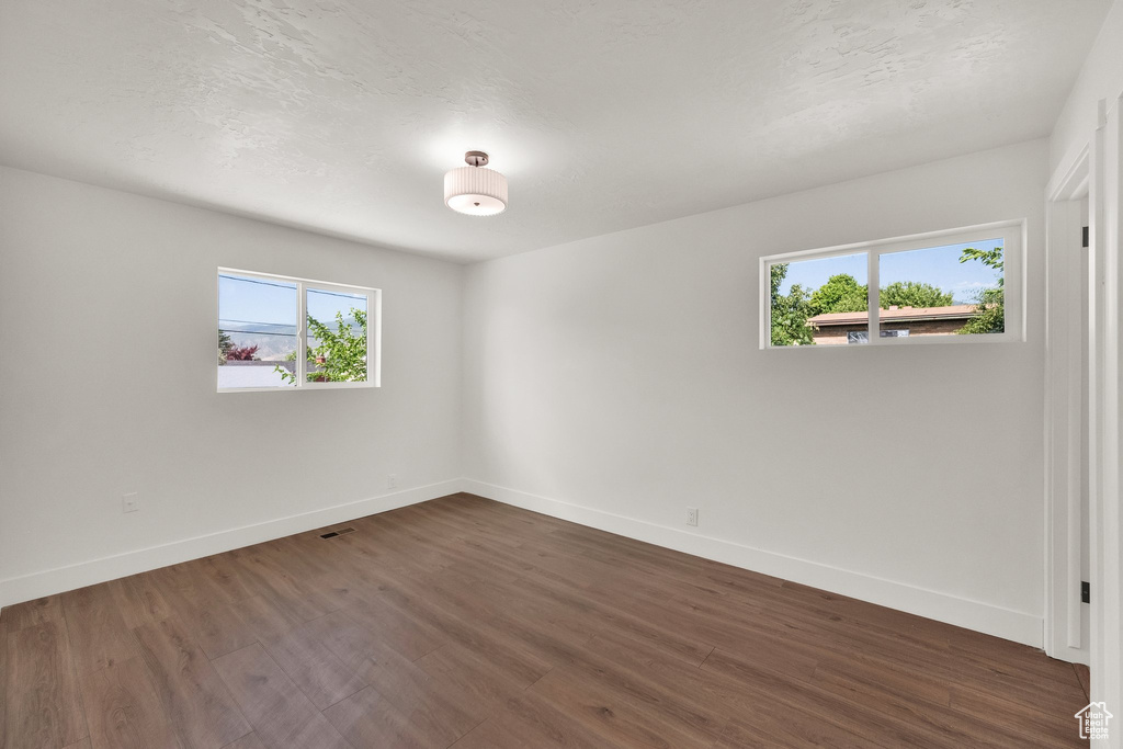 Unfurnished room with plenty of natural light and dark wood-type flooring