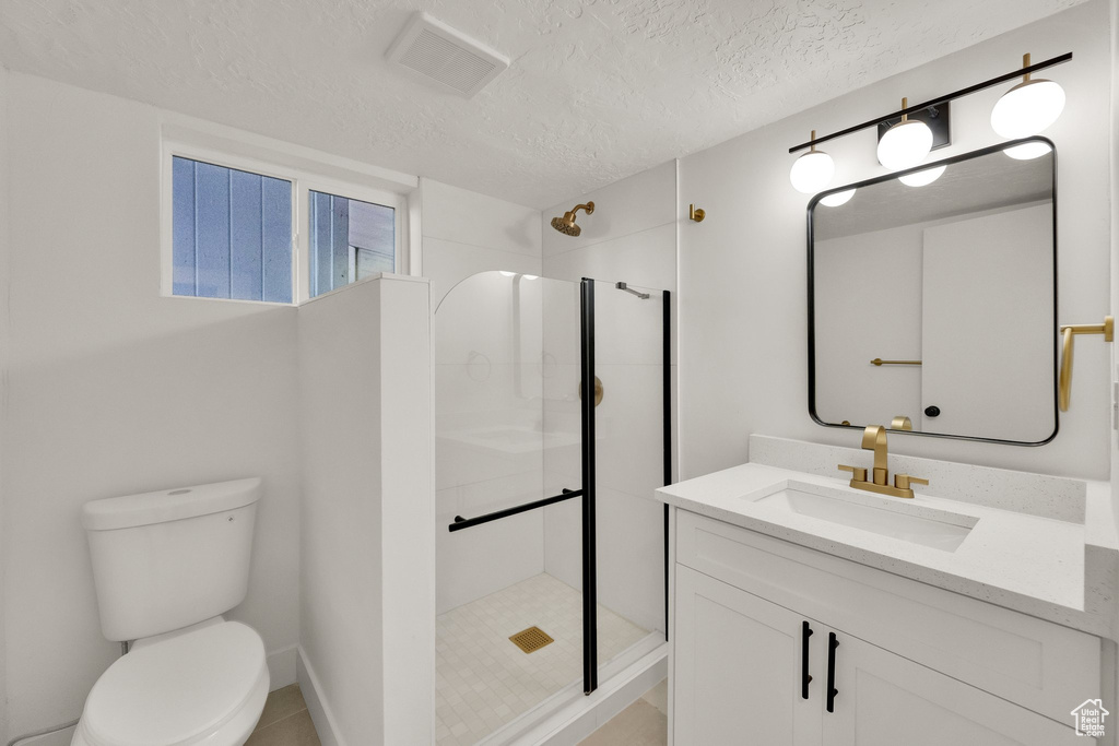 Full bathroom with vanity, tiled shower, and a textured ceiling