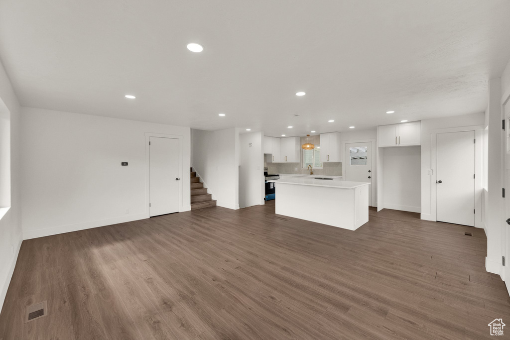 Unfurnished living room featuring stairway, recessed lighting, and wood finished floors