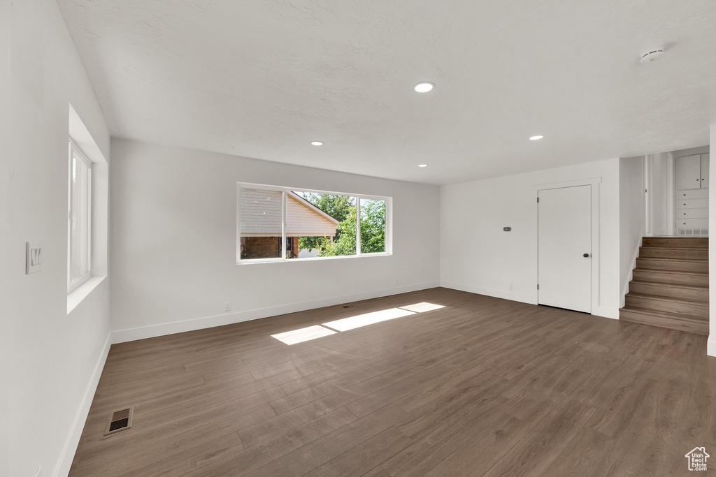 Unfurnished living room featuring dark wood finished floors, stairway, and recessed lighting