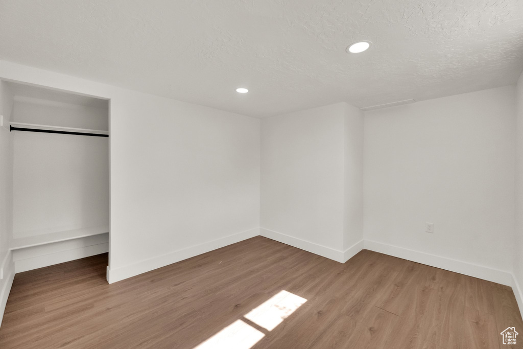 Unfurnished bedroom featuring wood finished floors, recessed lighting, a closet, and a textured ceiling