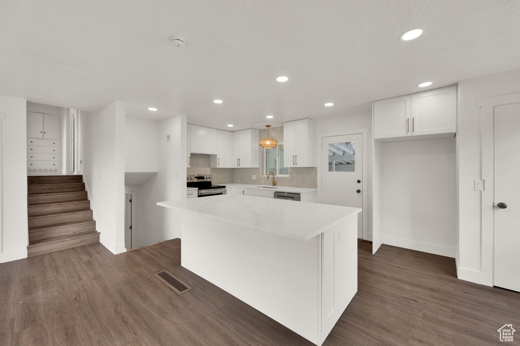 Kitchen with stainless steel range with electric stovetop, white cabinets, recessed lighting, a kitchen island, and light countertops