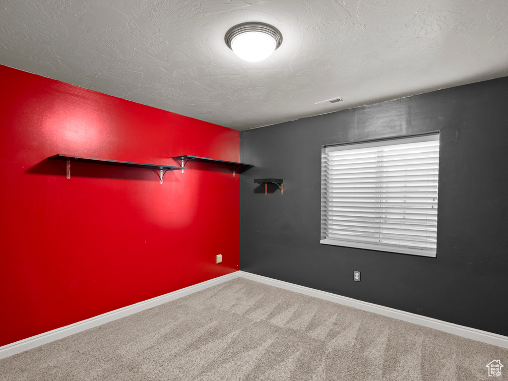 Empty room with carpet flooring and a textured ceiling