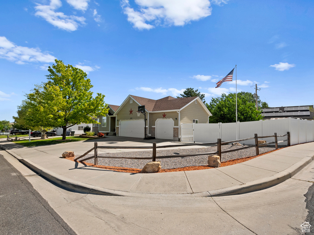 View of front of house with an attached garage, a fenced front yard, driveway, and a gate