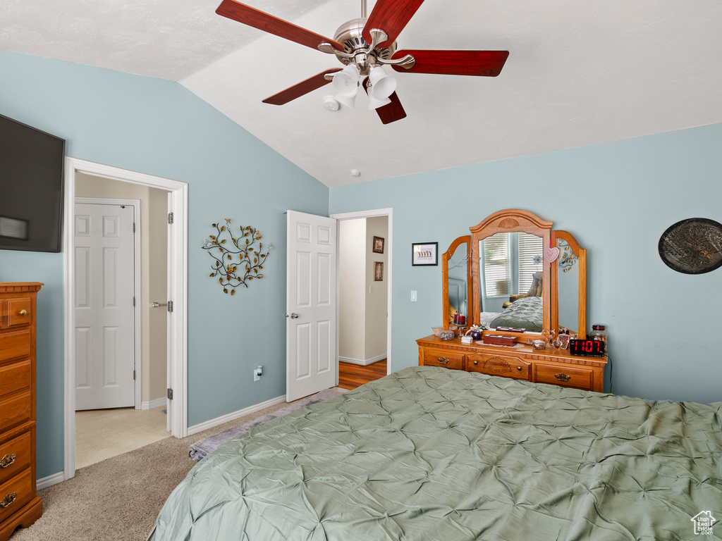 Carpeted bedroom with vaulted ceiling and a ceiling fan