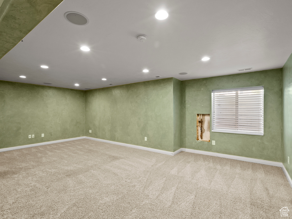 Carpeted empty room with a smoke detector and recessed lighting
