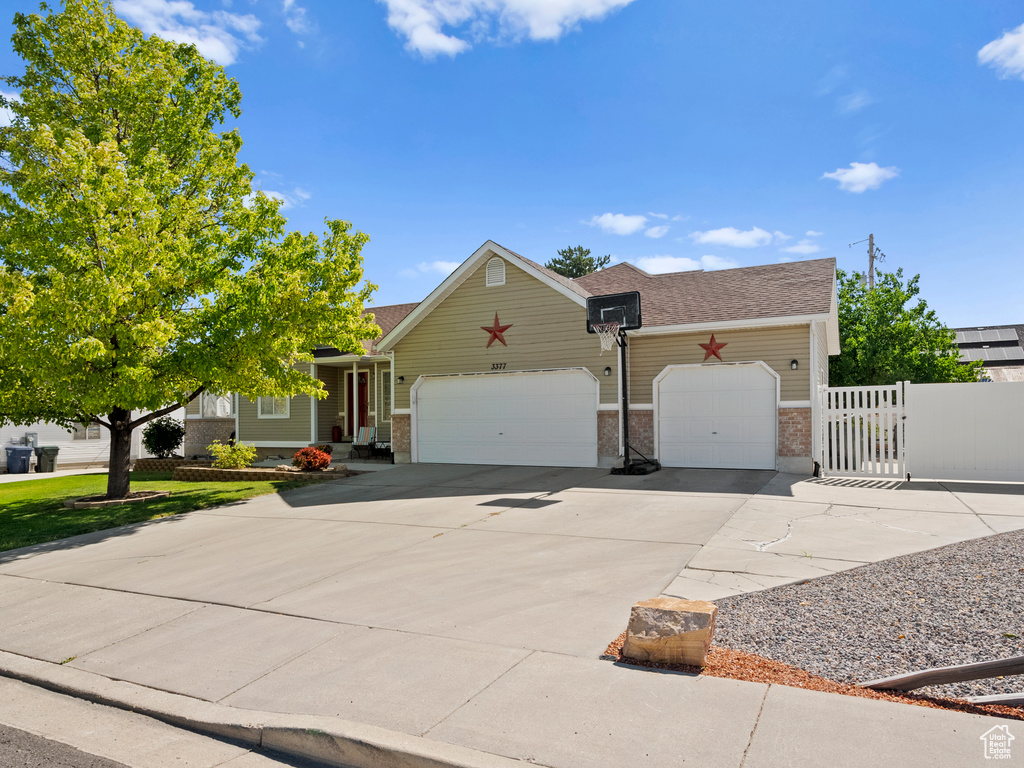 View of front of house with an attached garage, concrete driveway, brick siding, a gate, and a shingled roof