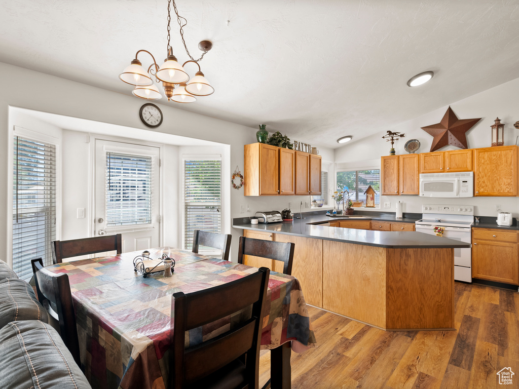 Dining space with a chandelier, lofted ceiling, and wood finished floors