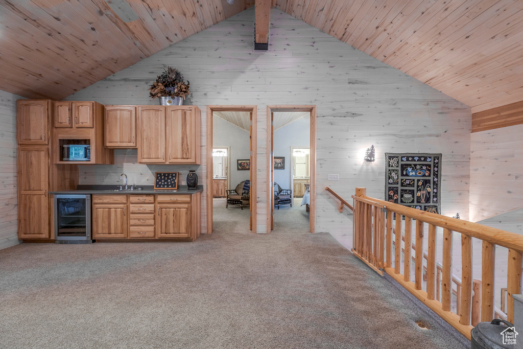 Bar featuring wine cooler, wooden walls, high vaulted ceiling, wood ceiling, and light carpet