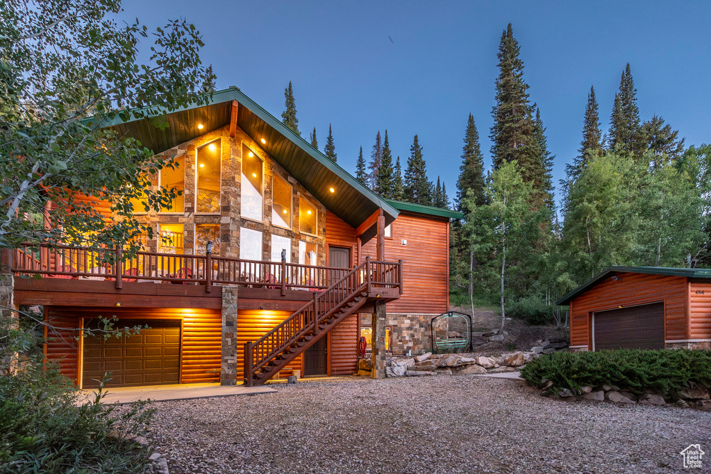 View of front of property with stone siding, an attached garage, a deck, and driveway