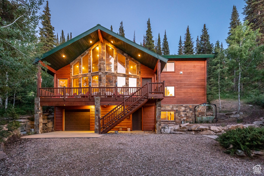 Chalet / cabin with stone siding, stairs, a garage, and driveway