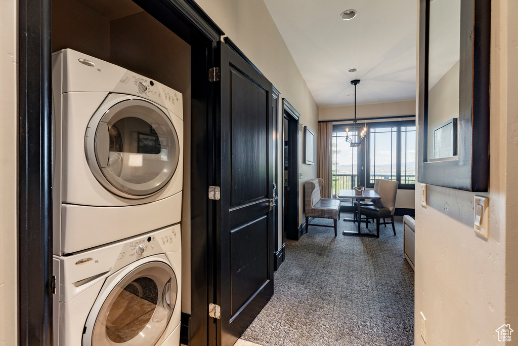 Laundry room featuring stacked washer and clothes dryer and dark carpet
