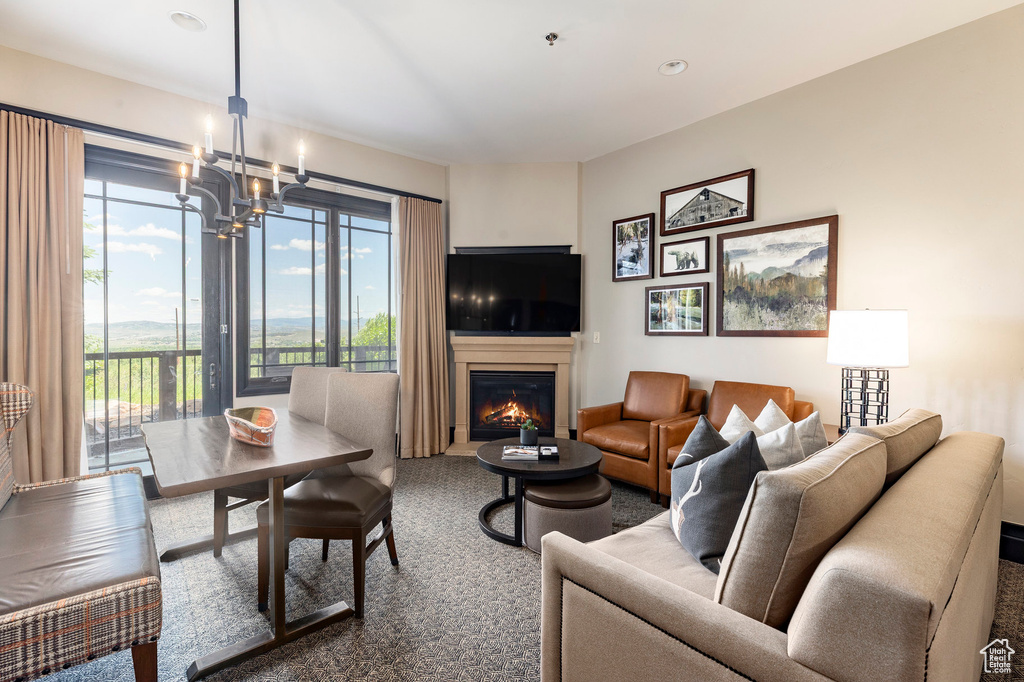 Living room featuring a glass covered fireplace, a chandelier, carpet flooring, and recessed lighting