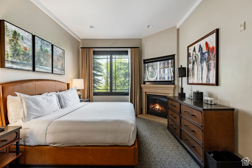 Bedroom with dark colored carpet and a glass covered fireplace