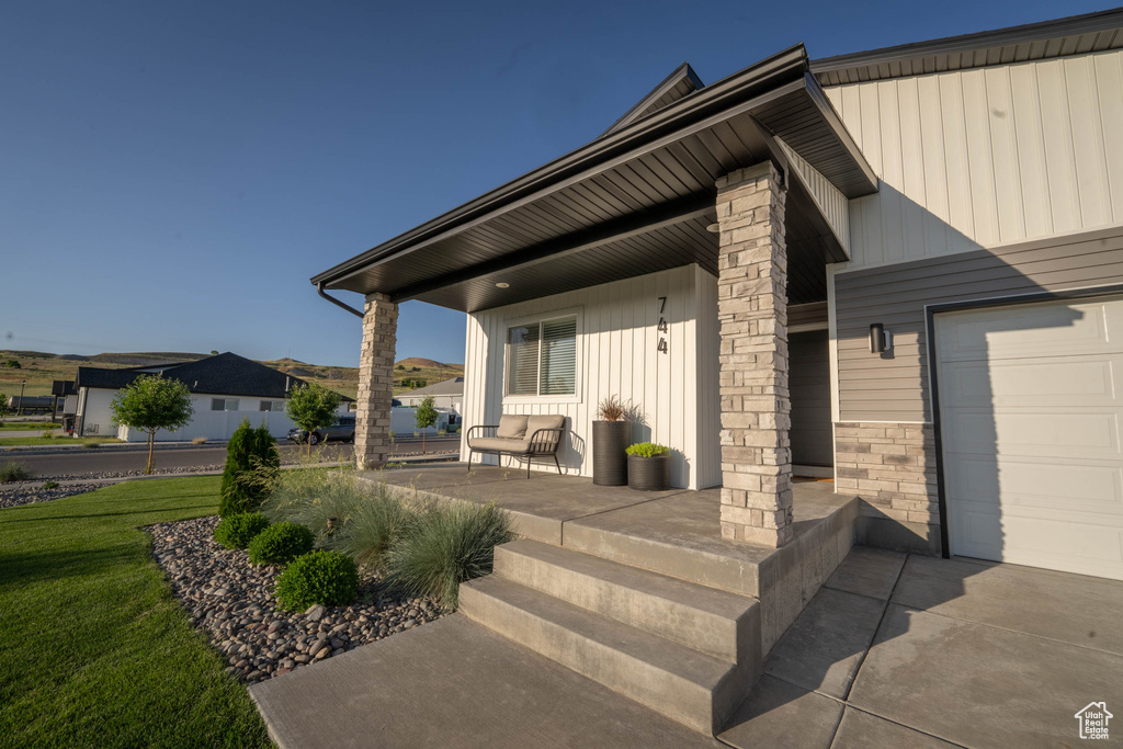 Covered porch featuring a lawn and a garage