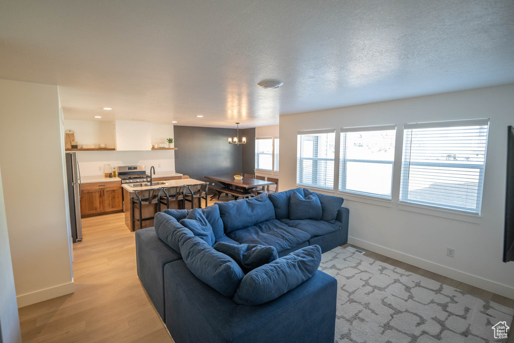 Living room with a chandelier, light wood-style flooring, and recessed lighting