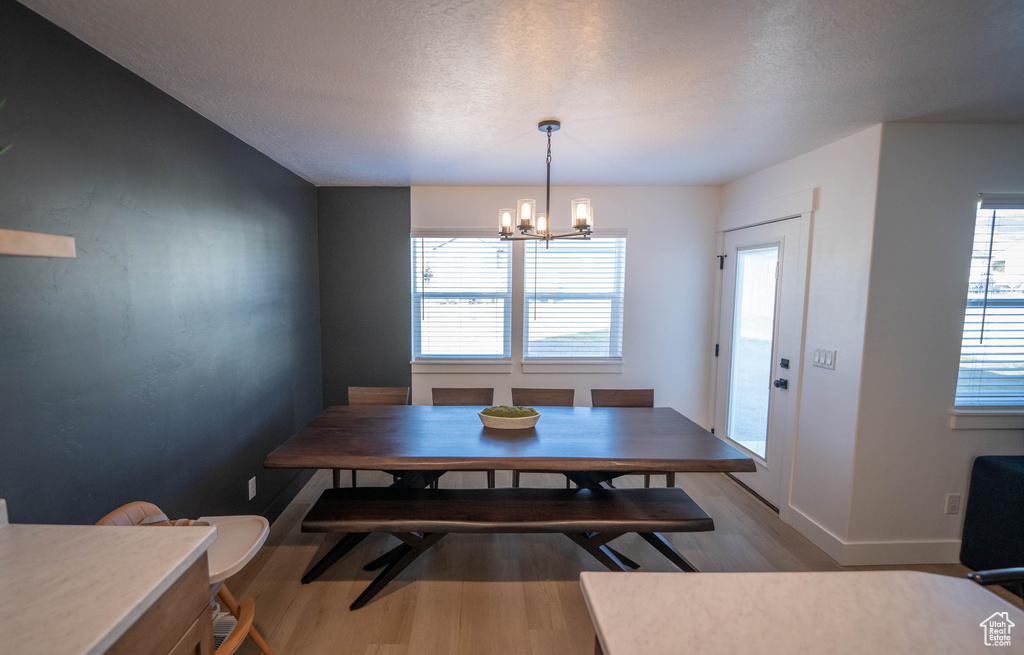 Dining area with wood finished floors, a chandelier, and a textured ceiling