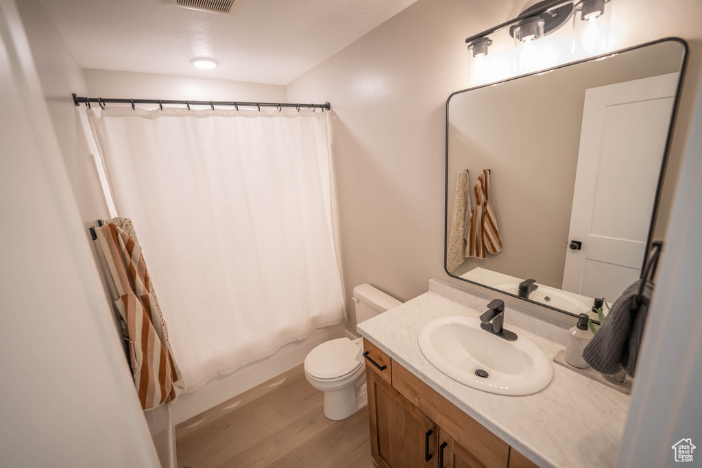 Full bath featuring vanity, wood finished floors, and shower / bath combination with curtain