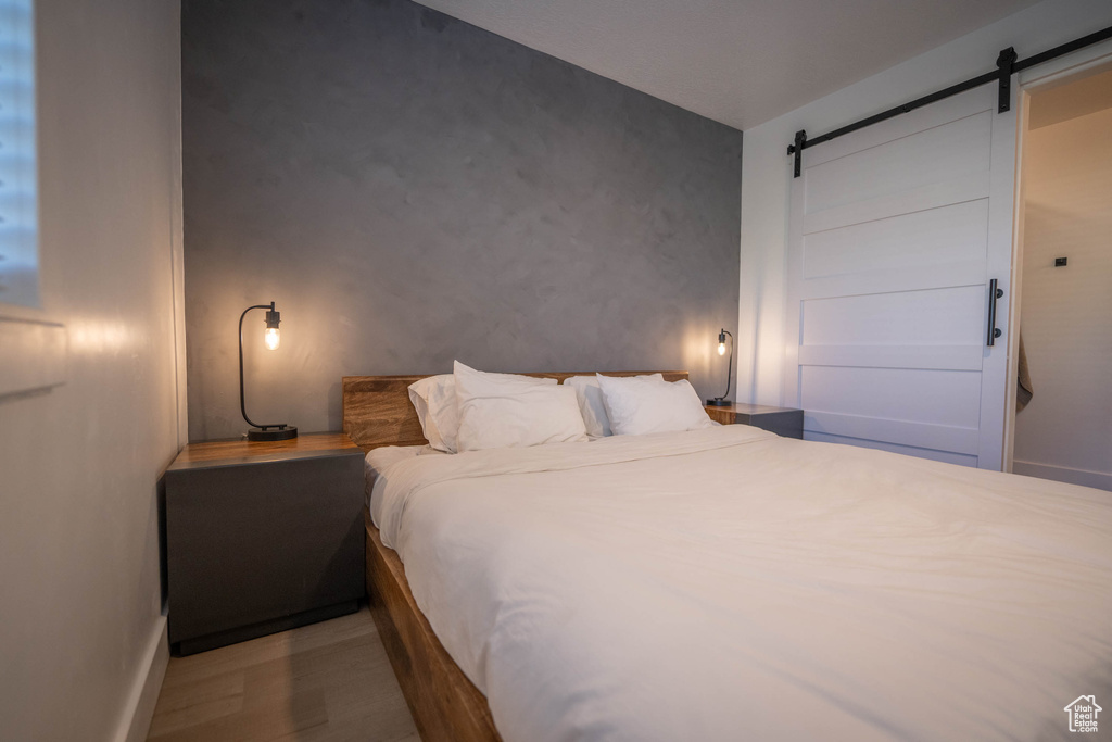 Bedroom with a barn door and wood finished floors