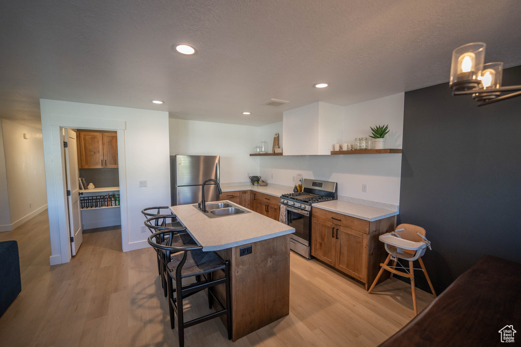 Kitchen with appliances with stainless steel finishes, open shelves, light wood-style floors, brown cabinets, and light countertops
