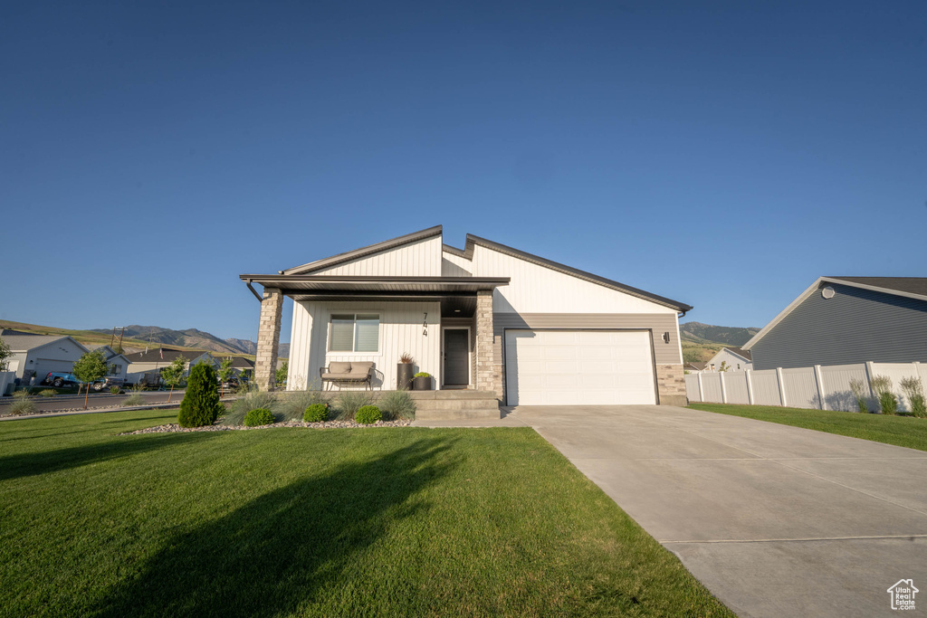 View of front of property with a garage, concrete driveway, a mountain view, and a porch