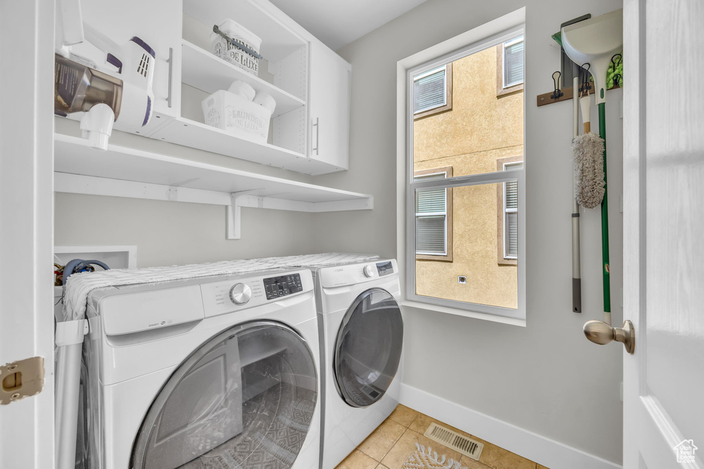 Laundry area featuring independent washer and dryer, cabinet space, and light tile patterned flooring