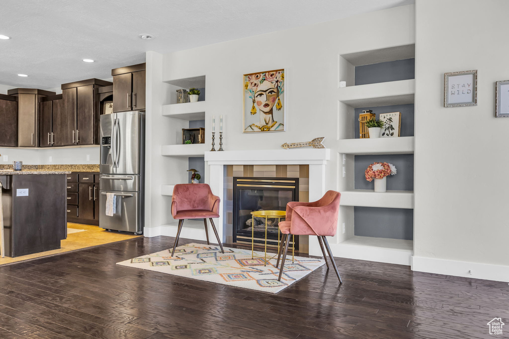 Living area with built in features, light wood-type flooring, recessed lighting, and a tile fireplace