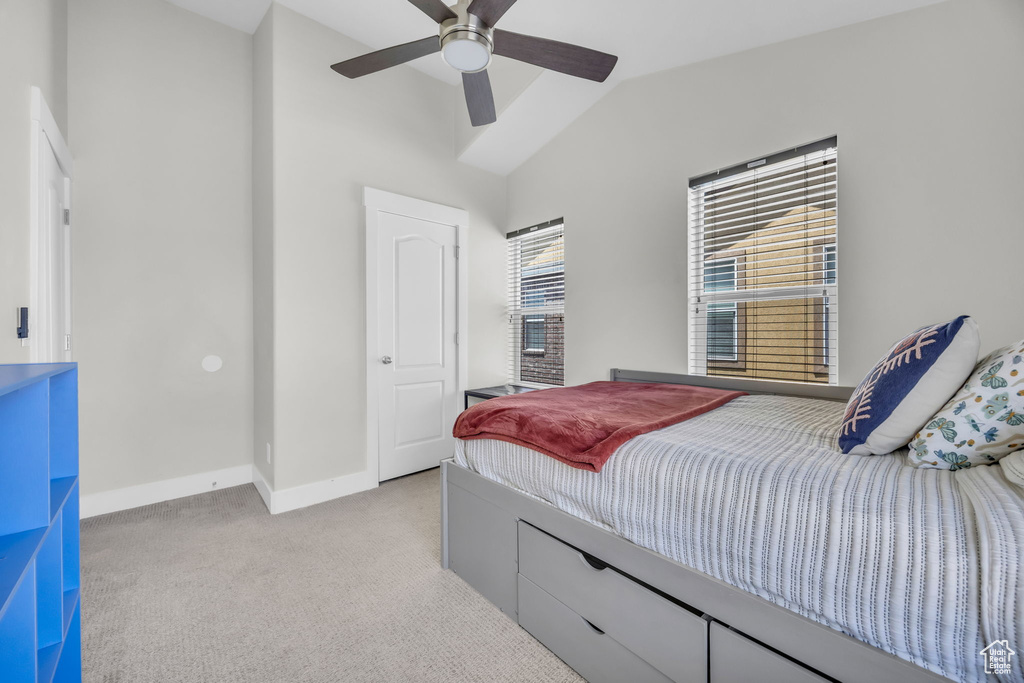 Bedroom with light colored carpet, vaulted ceiling, and a ceiling fan