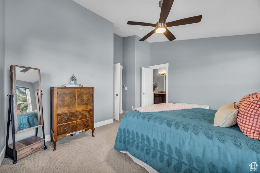 Carpeted bedroom with high vaulted ceiling, a ceiling fan, and ensuite bathroom