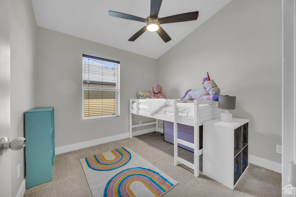Carpeted bedroom featuring vaulted ceiling and ceiling fan