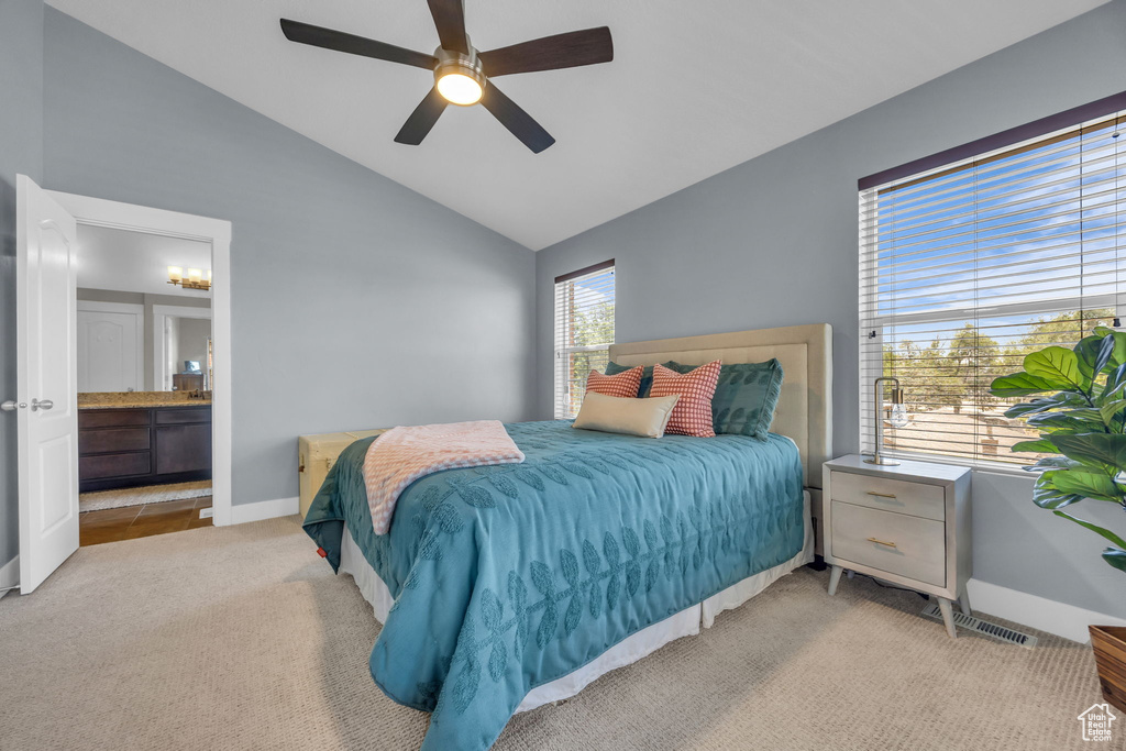 Bedroom with light carpet, ensuite bath, ceiling fan, and high vaulted ceiling
