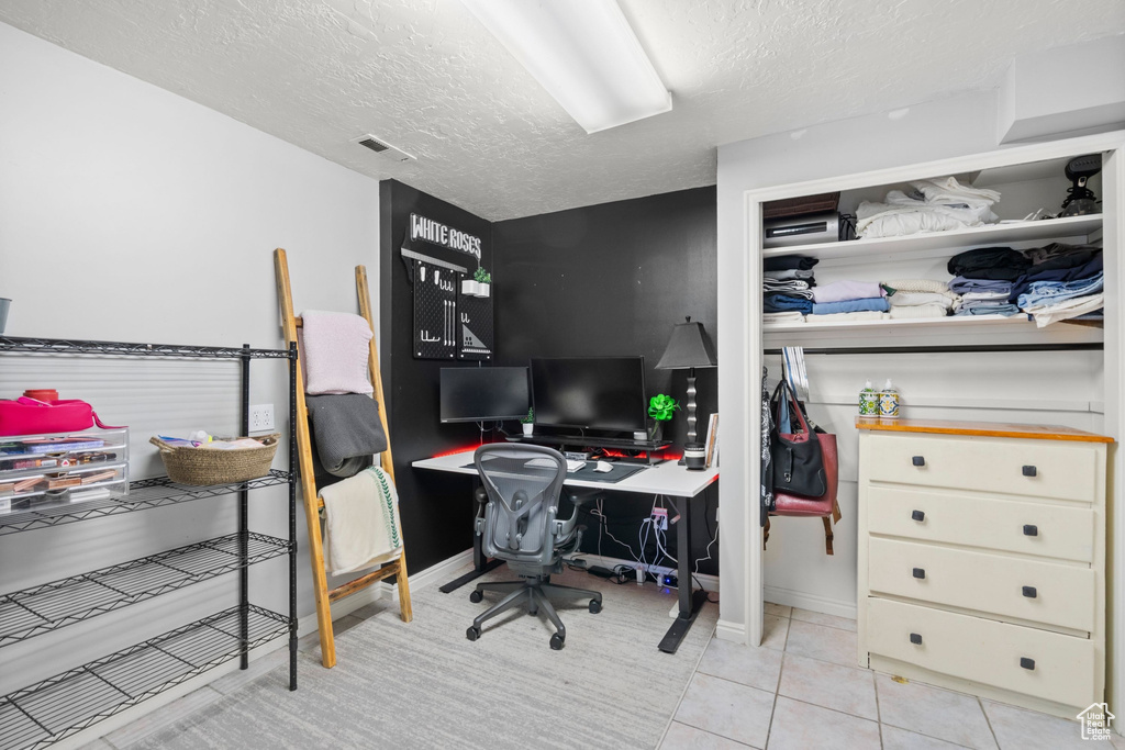 Tiled office space featuring a textured ceiling and baseboards