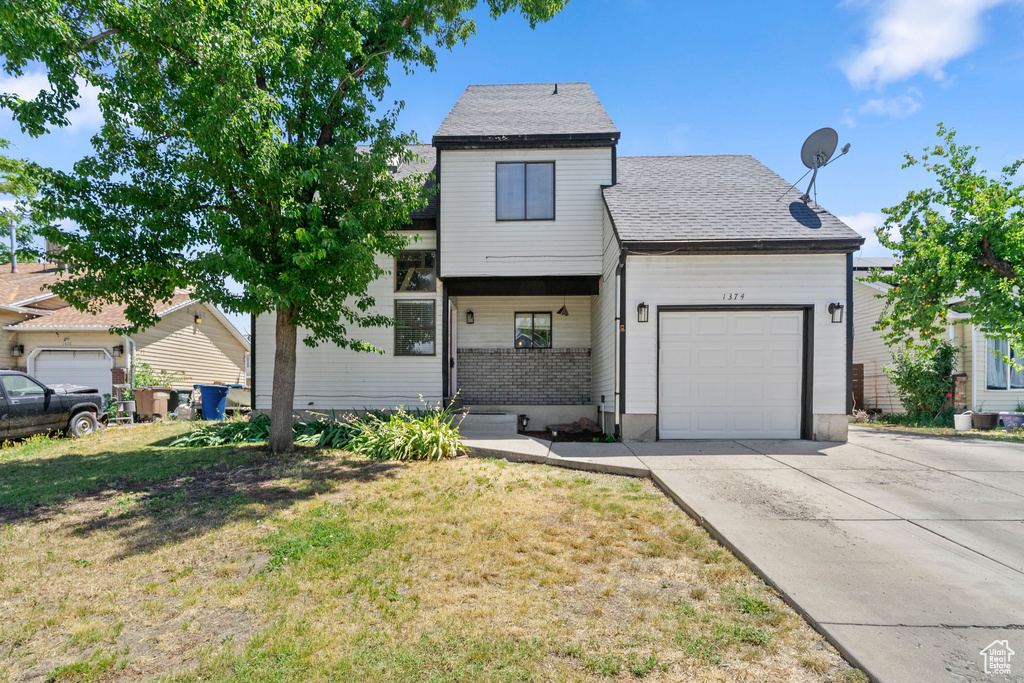View of front of property with a garage, concrete driveway, a front lawn, and roof with shingles