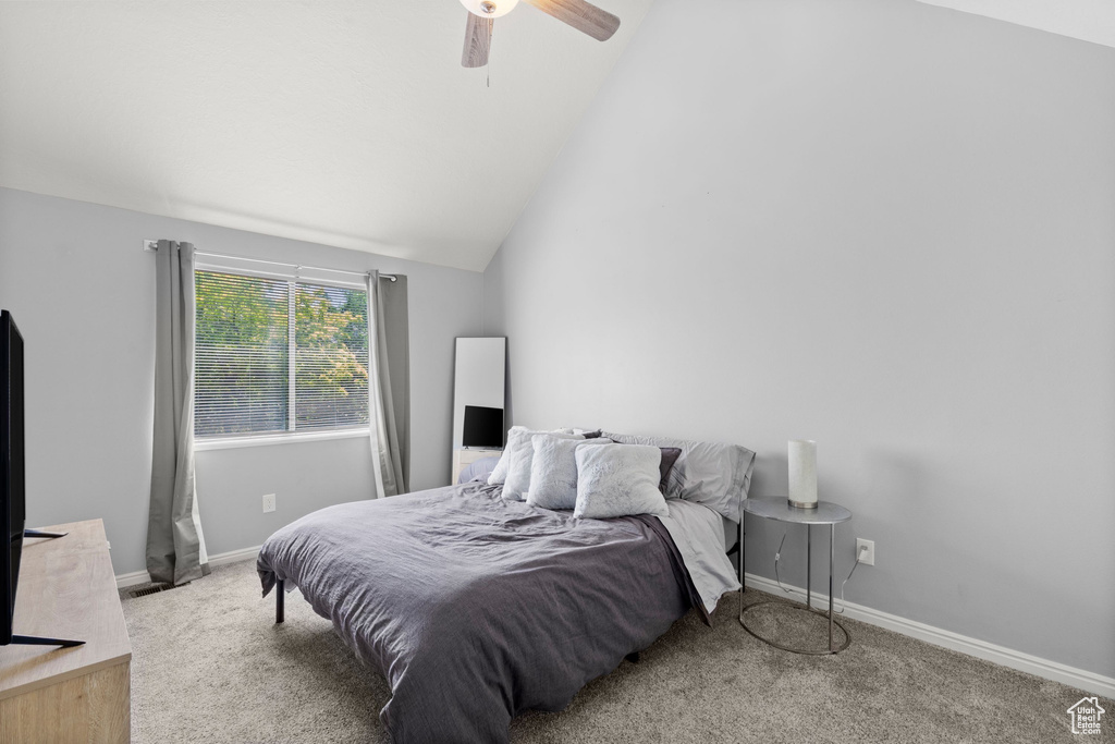 Carpeted bedroom featuring vaulted ceiling and ceiling fan