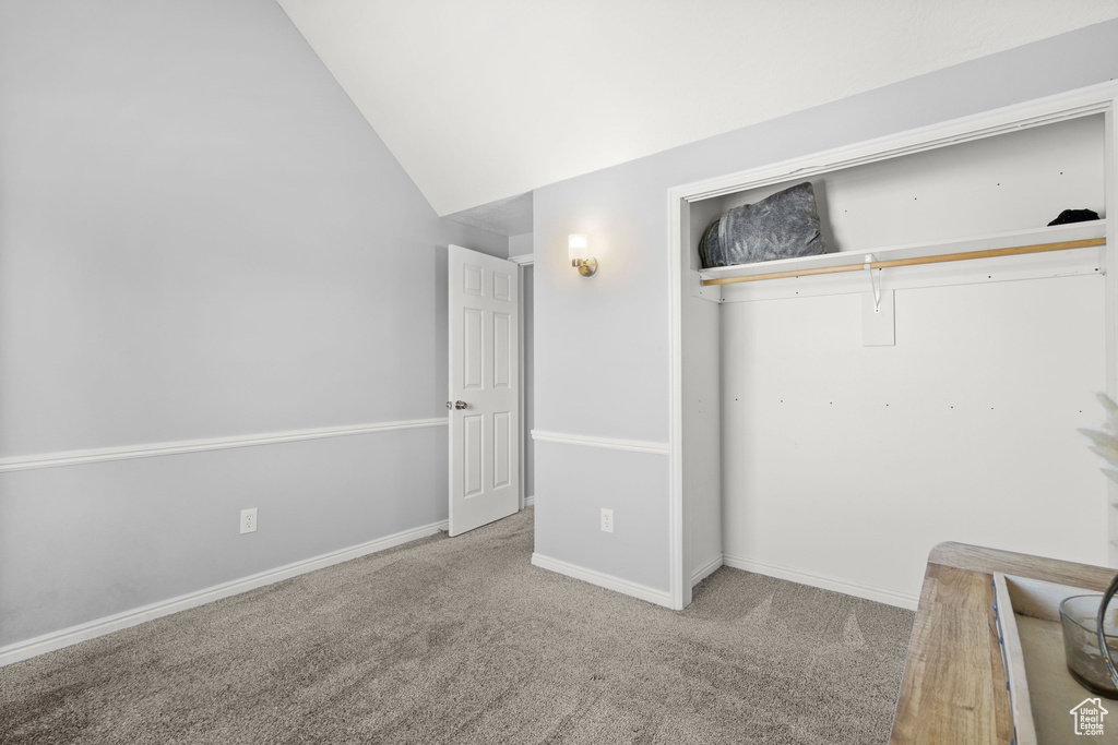 Unfurnished bedroom with carpet flooring, a closet, and vaulted ceiling