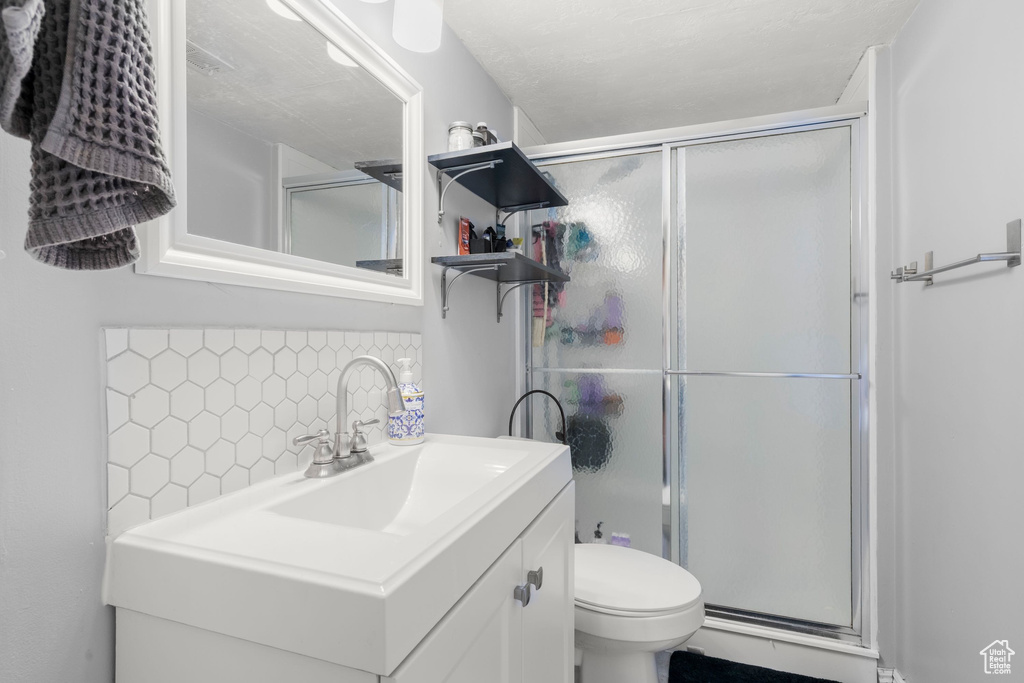 Full bathroom featuring a stall shower, backsplash, and vanity