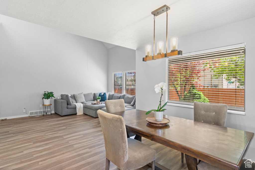 Dining room featuring light wood-type flooring and vaulted ceiling