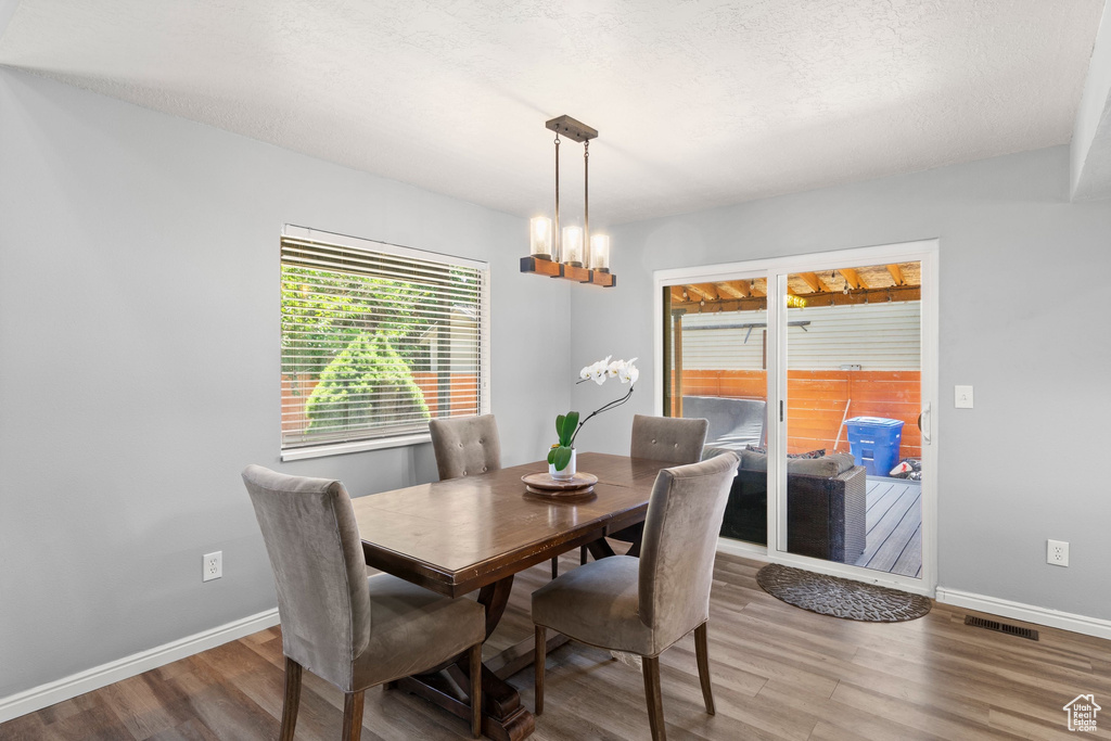 Dining area with wood finished floors and a chandelier