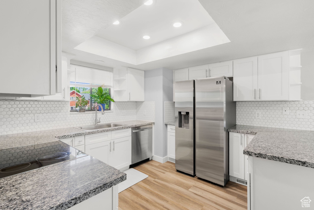 Kitchen featuring appliances with stainless steel finishes, open shelves, a raised ceiling, white cabinetry, and recessed lighting