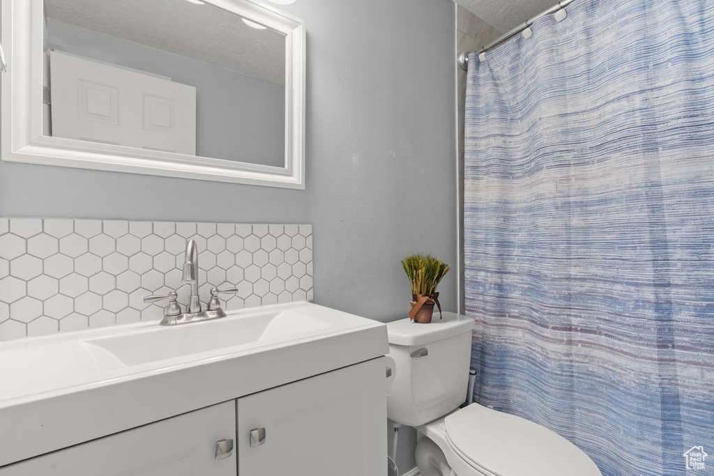Full bathroom with tasteful backsplash, vanity, a shower with shower curtain, and a textured ceiling