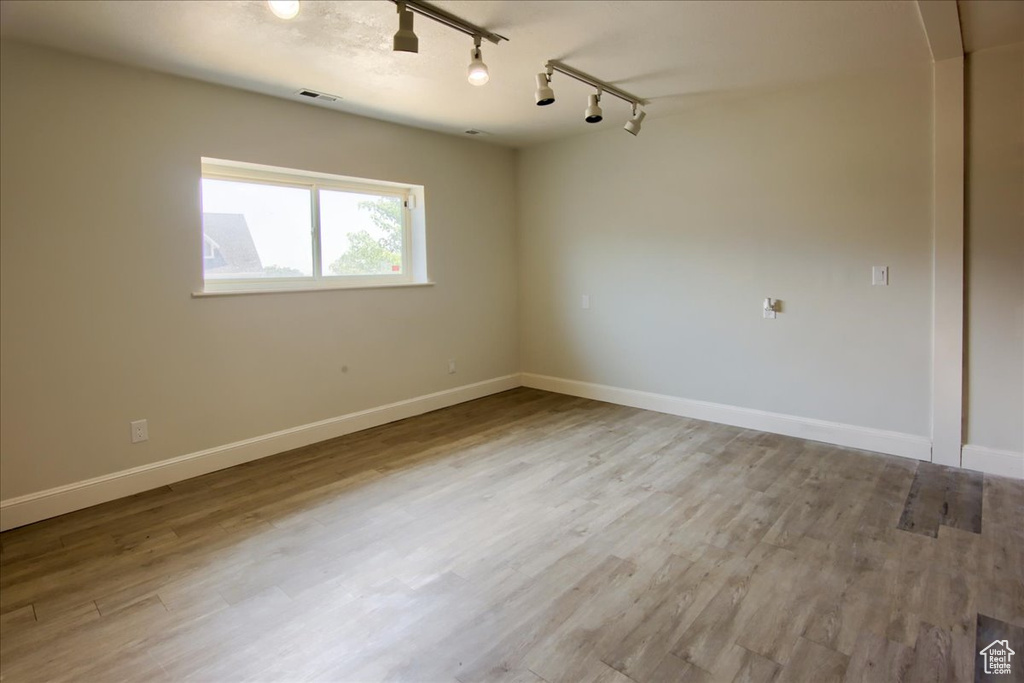 Spare room featuring rail lighting, wood finished floors, and arched walkways