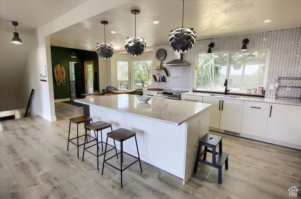 Kitchen featuring a breakfast bar, a center island, light wood-style floors, and recessed lighting
