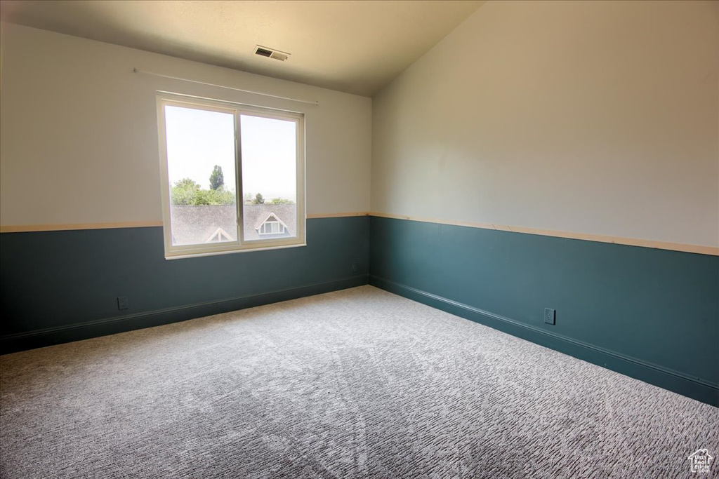 Carpeted spare room featuring baseboards