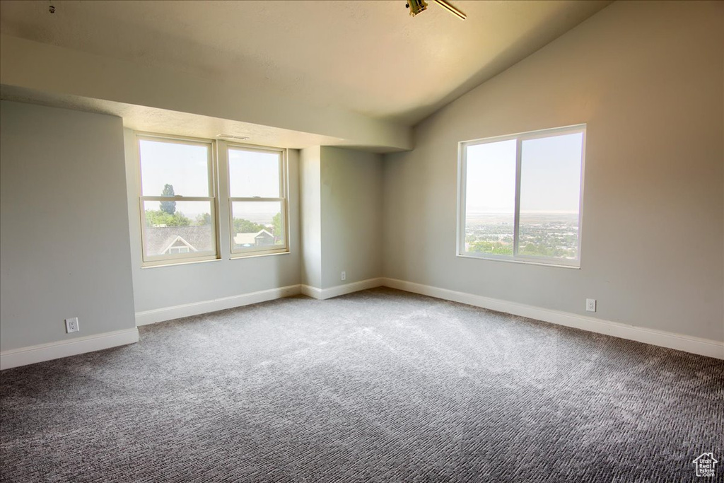 Spare room featuring carpet flooring and vaulted ceiling