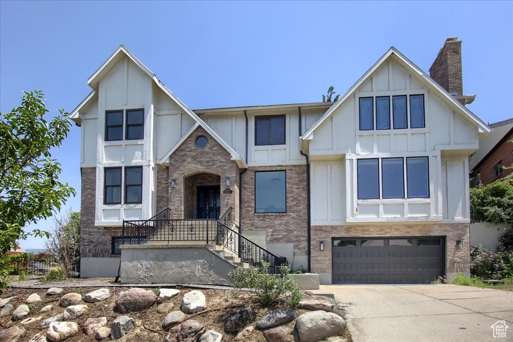 Tudor home featuring brick siding, board and batten siding, a garage, and concrete driveway