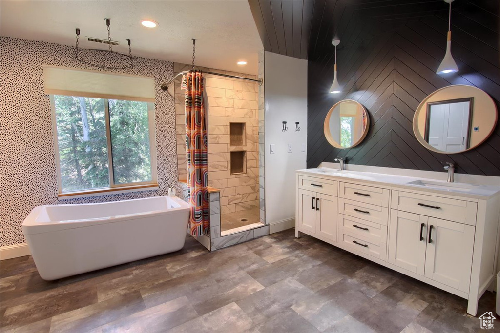 Bathroom with a shower stall, a soaking tub, double vanity, and recessed lighting