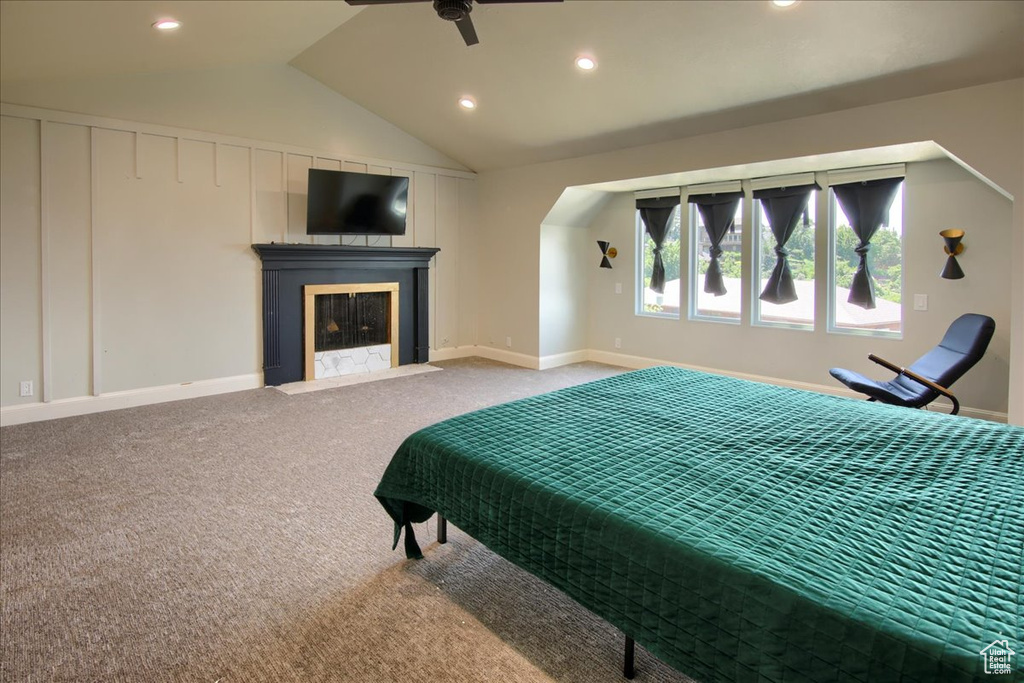 Bedroom with recessed lighting, lofted ceiling, carpet flooring, a fireplace with flush hearth, and arched walkways
