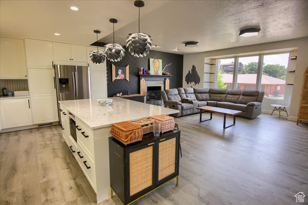 Kitchen with light wood-style floors, white cabinets, a fireplace, light stone counters, and recessed lighting