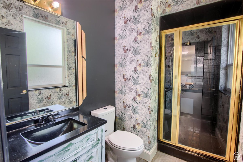 Full bath featuring wallpapered walls, vanity, and a shower stall